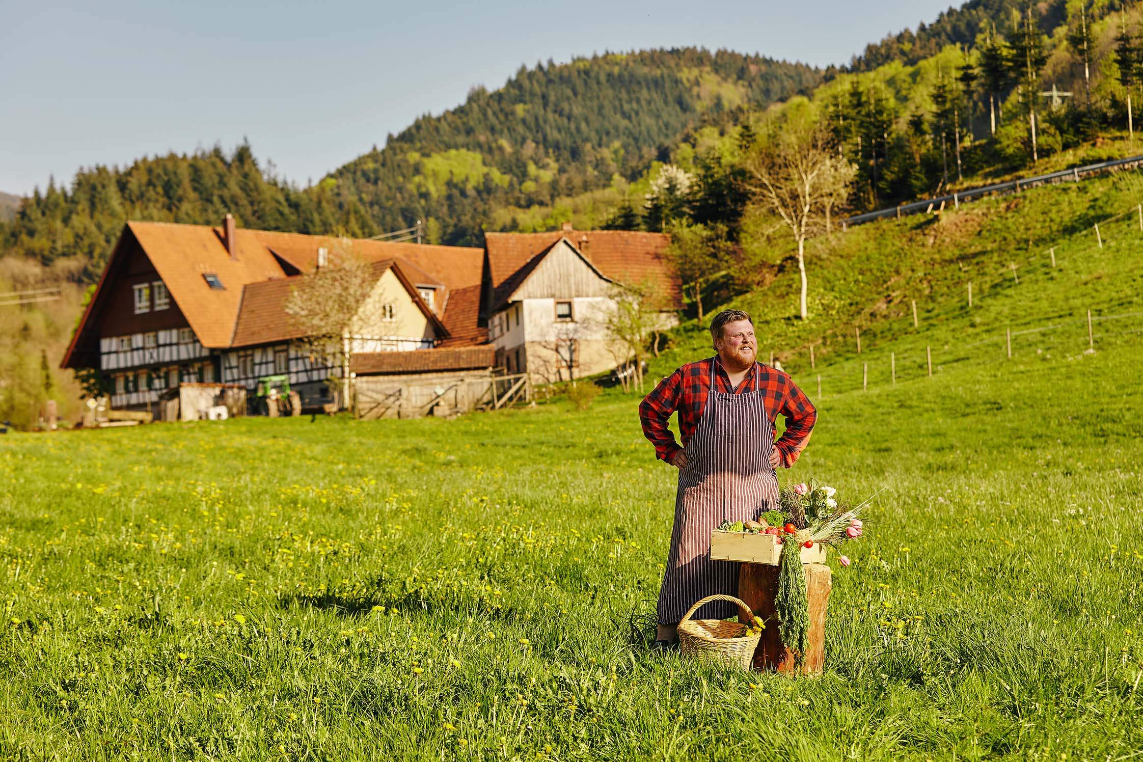 Porträt von Timo Franke, veganer Koch, im Schwarzwald auf der grünen Wiese vor dem Hof seiner Großeltern.